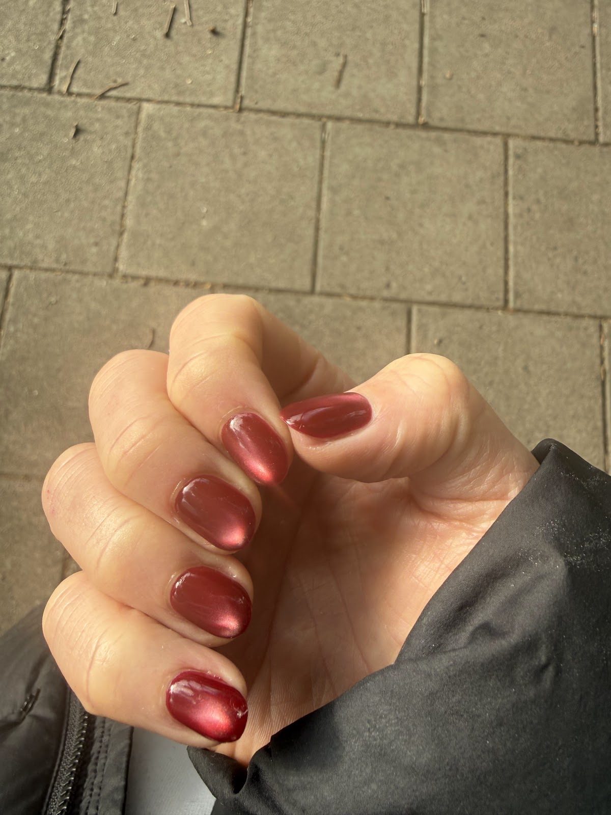 A hand showing glossy metallic red chrome nails